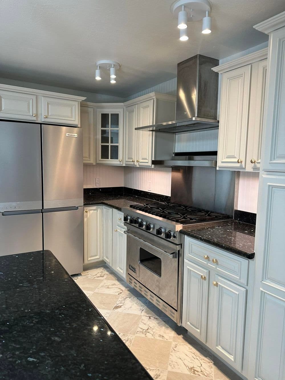 Modern kitchen with white cabinets, stainless steel appliances, and black granite countertops.